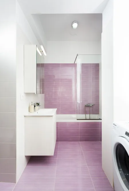 Purple-themed bathroom with bath tub and washing machine